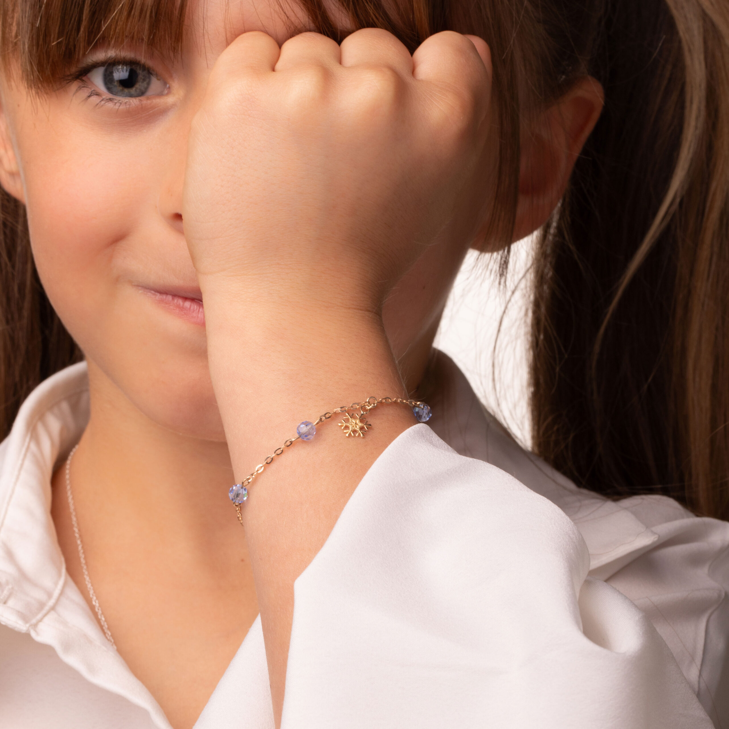 Złota bransoletka dziecięca Disney 9kt z zawieszką śnieżynką i niebieskimi kryształkami 3 Złota bransoletka dziecięca Disney 9kt z zawieszką śnieżynką na ręku dziewczynki