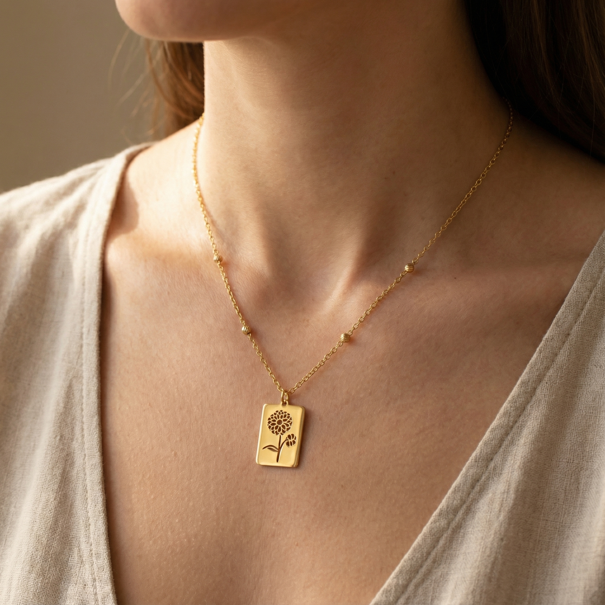Naszyjnik złoty (1,93g) z prostokątną zawieszką – motyw kwiatu | BigDIAMOND Kraków 1 A close-up of a gold necklace featuring a floral design, worn by a woman.